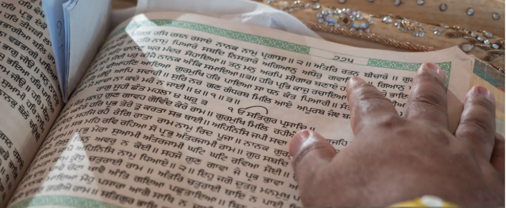 Hands resting on an open Guru Granth Sahib